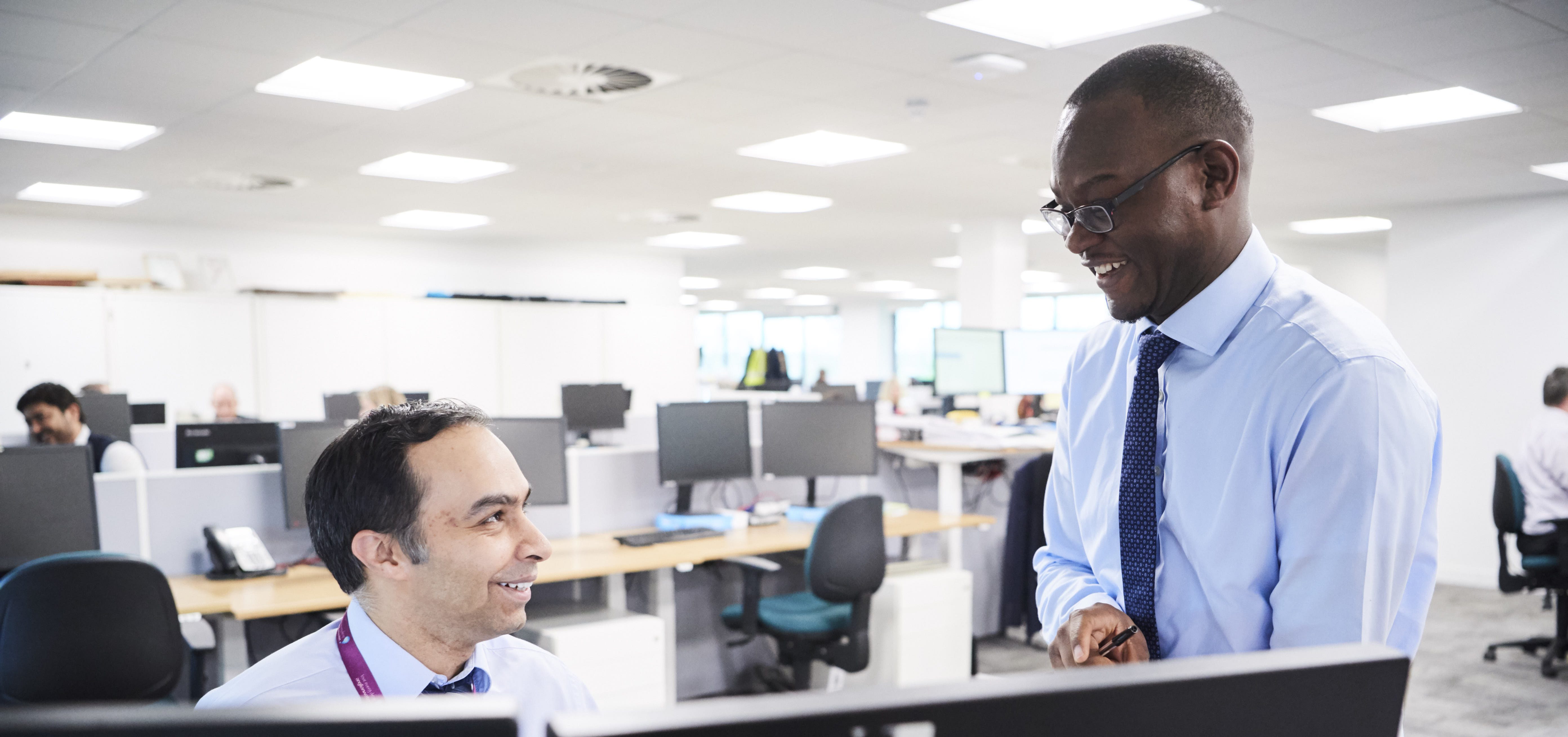 Two male co-workers in office environment talking