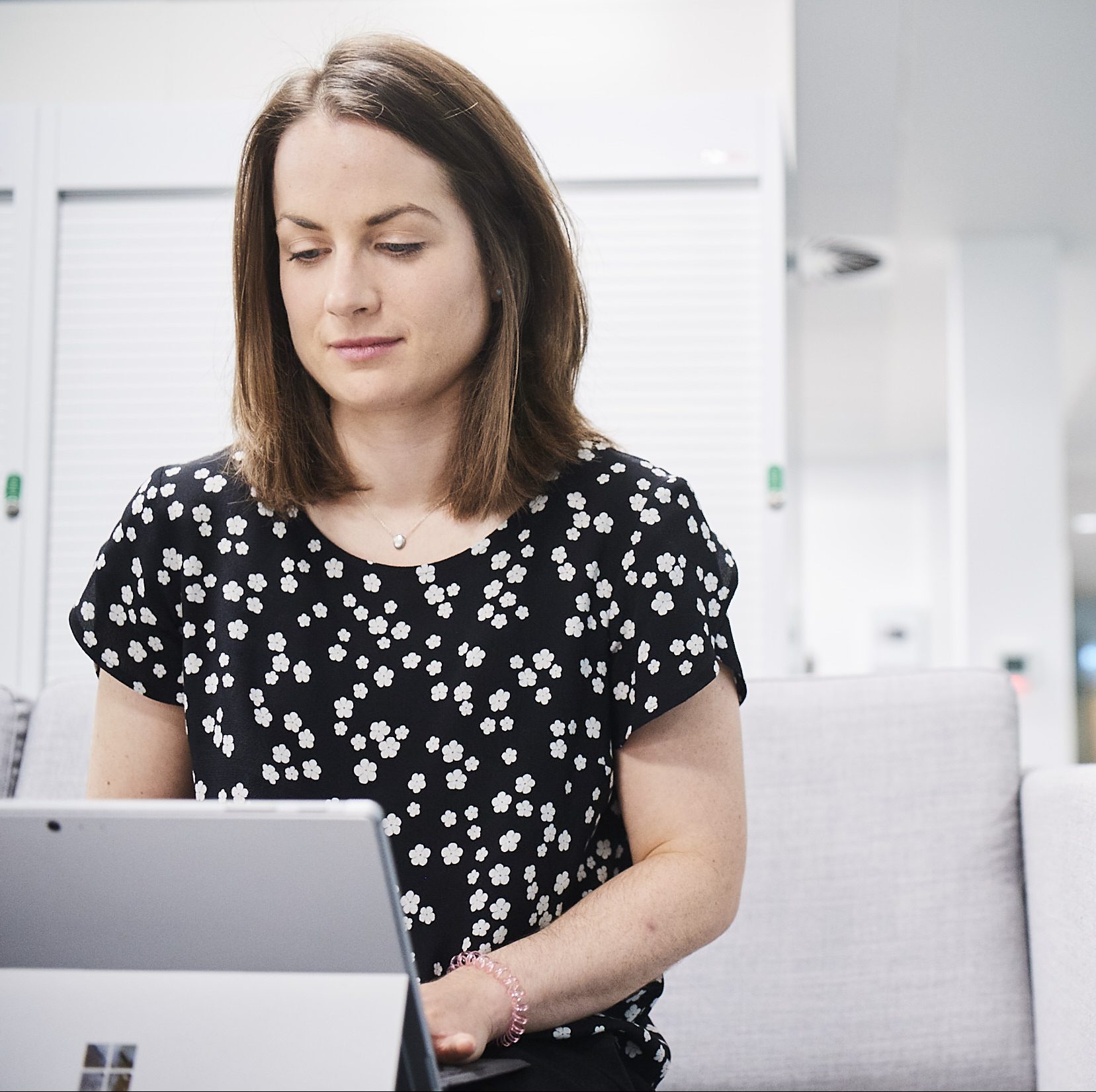 Female in an office environment on sofa using tablet