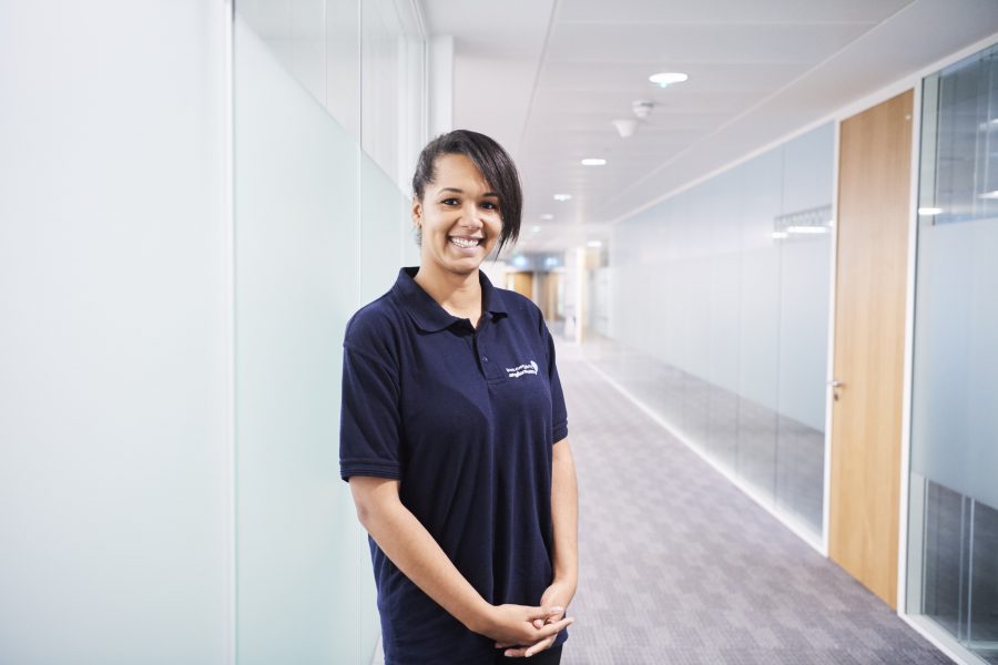 Young woman in Anglian Water polo shirt standing in an office corridor