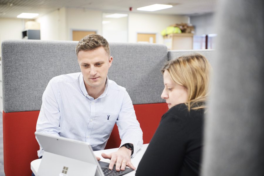 Female and male co-workers sitting in booth in office environment using a table device