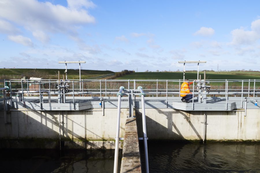 Male in high vis jacket on top of water treatment building checking gauges