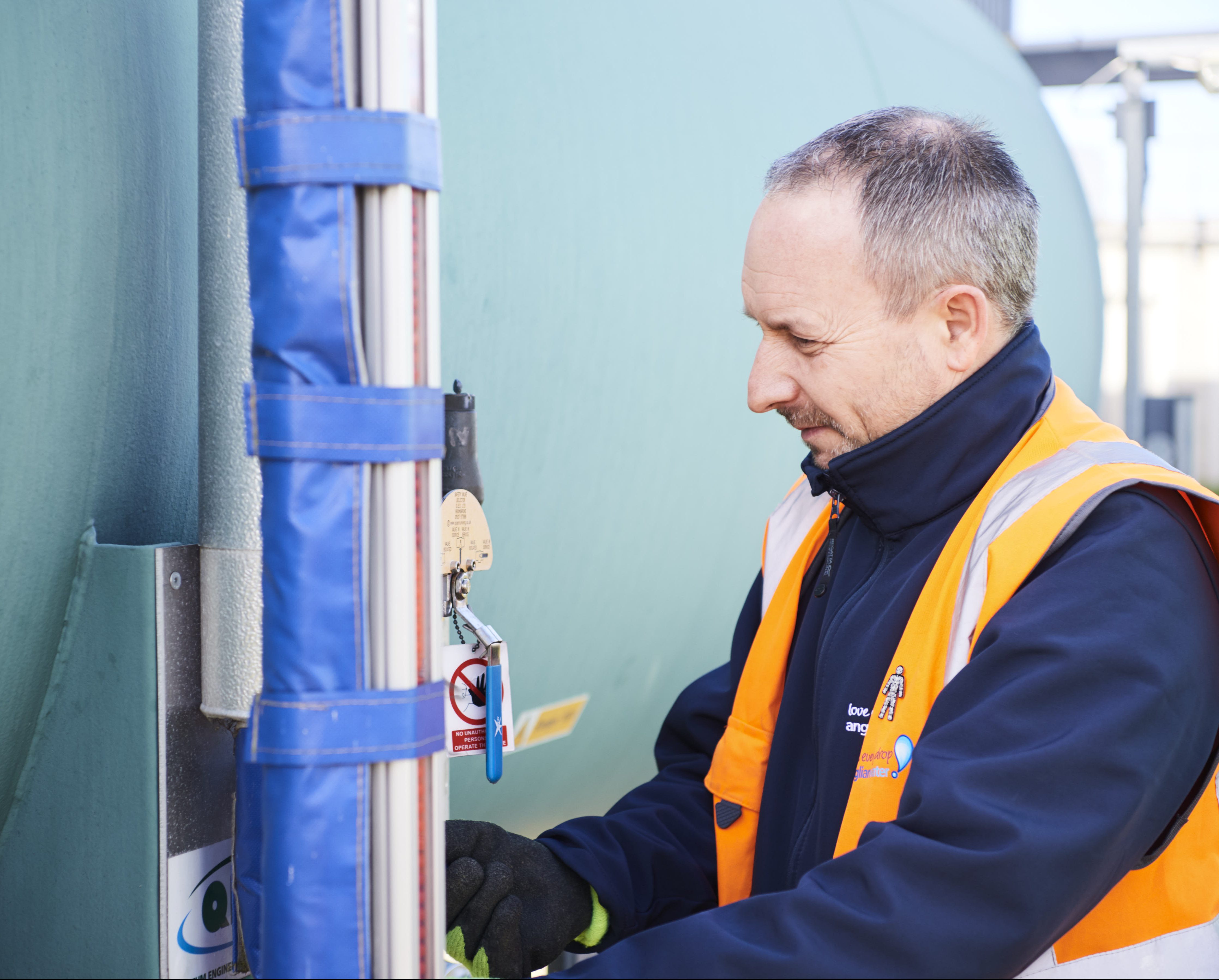 Man in high vis vest and gloves making adjustments to a piece of machinery at a treatment facility