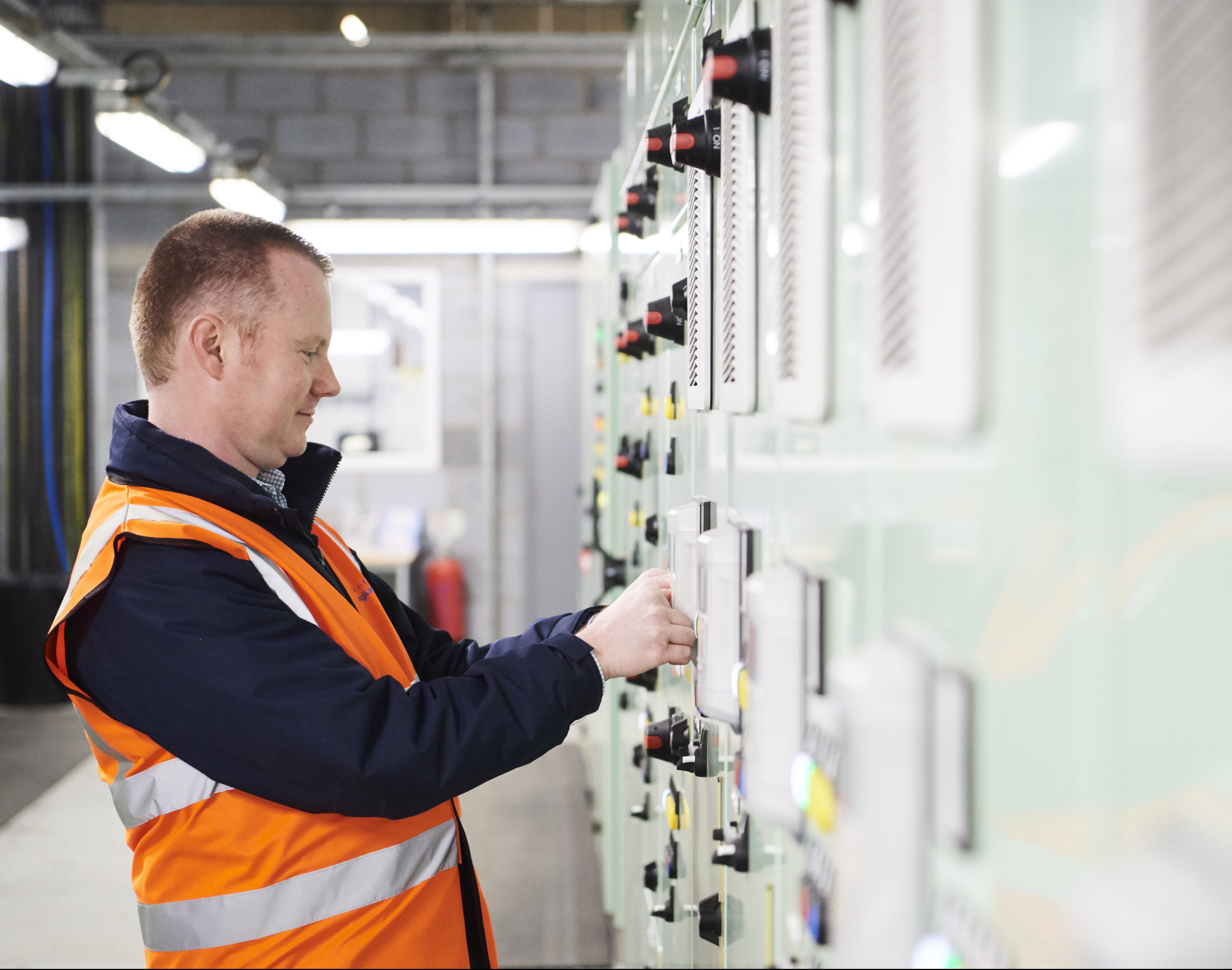 Male in high vis jacket pushing buttons on machine in water treatment centre