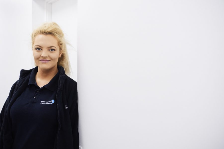 Young woman in Anglian Water polo shirt and fleece coat standing in an office doorway