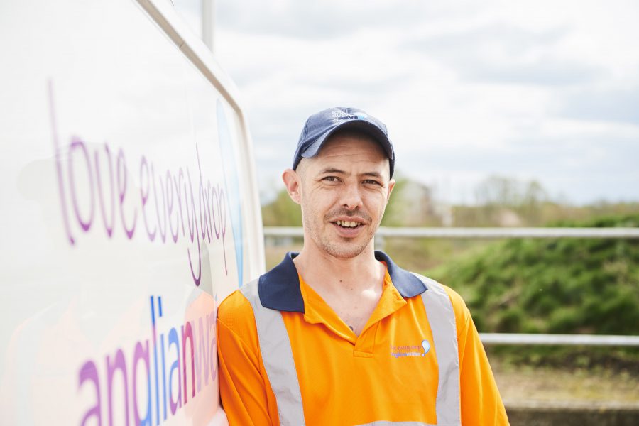 Head and torso shot of a man in a high vis top leaning against an Anglian Water van