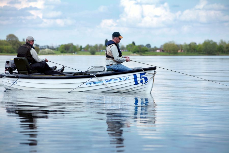 Two males in fishing boat on water at Rutland Water