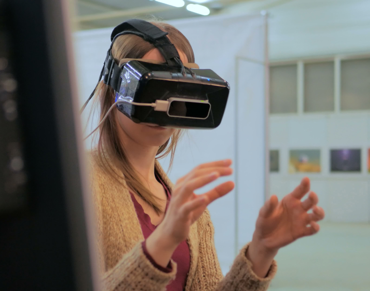 Woman in an office environment wearing a VR headset, hands out in front of her