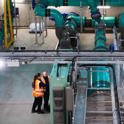 Overheard view of man and woman looking at machinery inside a treatment works